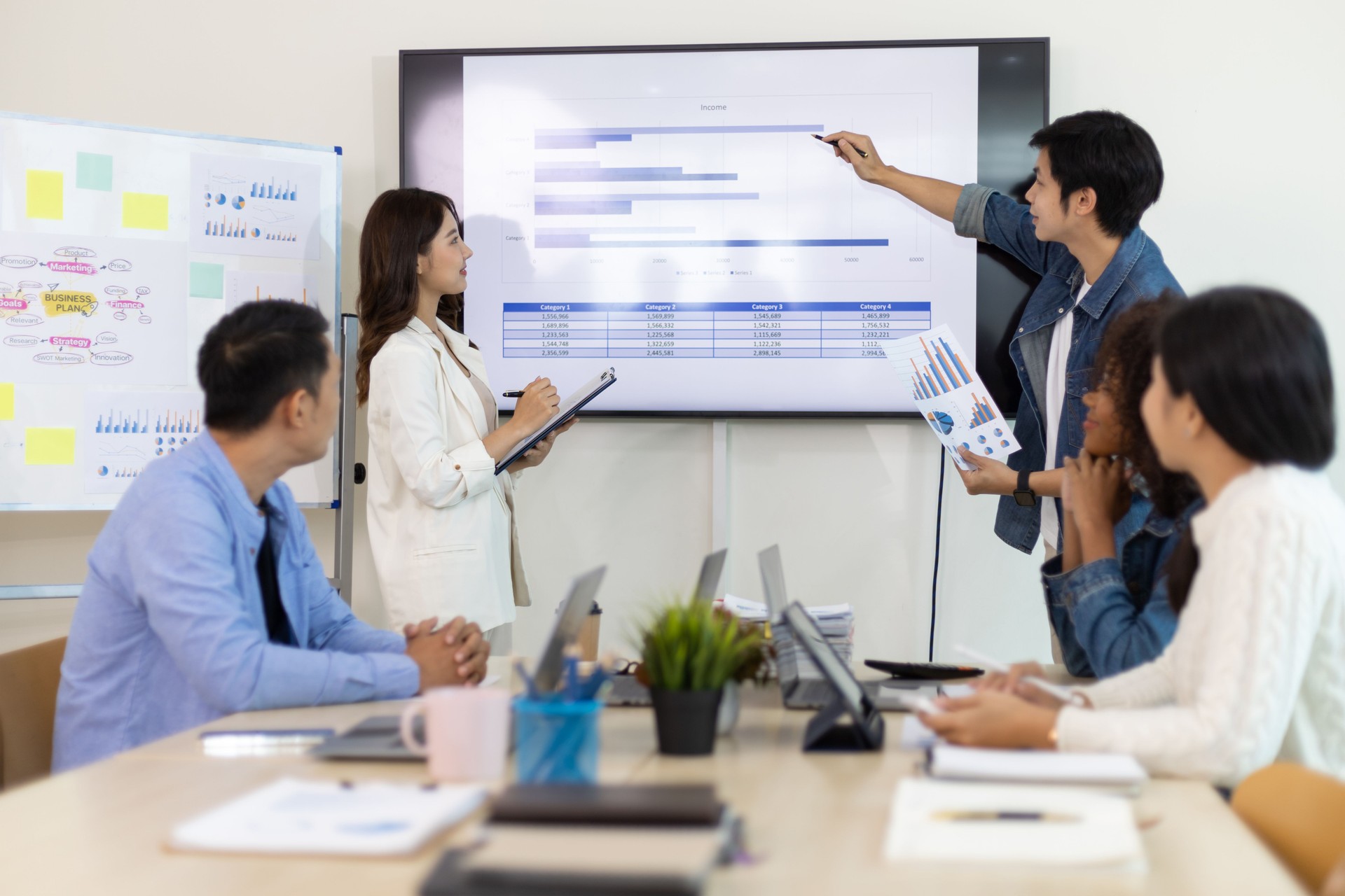 Professional marketer is making a presentation during a planning business meeting with colleagues. Meeting of diverse young entrepreneurs, talking, Businesspeople develop startup.