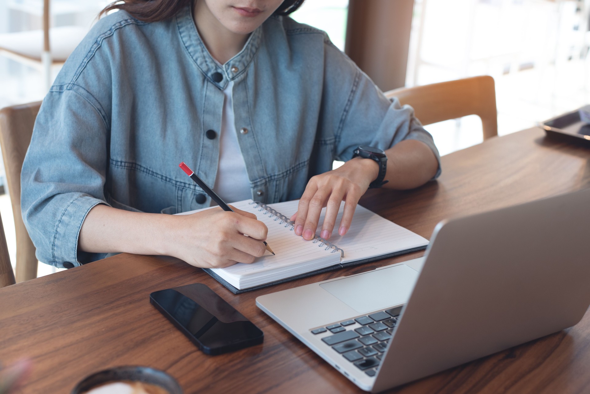 Young asian business woman working on laptop computer and planning work project on notebook, e-learning, remote work, Female student studing online class via laptop computer and writing on notebook, doing homework at home.